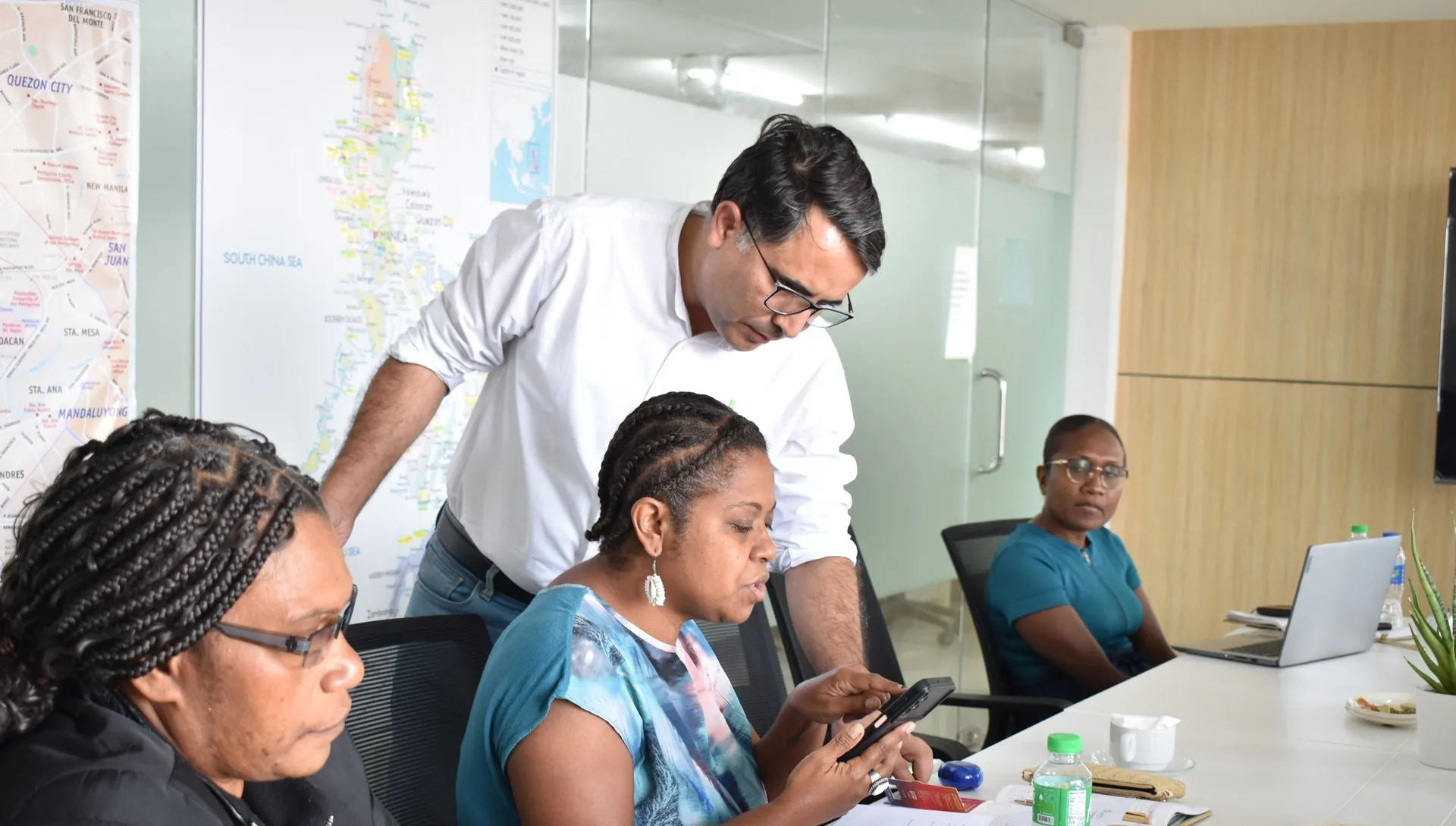 Getmeds Healthcare colleagues reviewing an order together in a meeting room, a map of the Philippines on the wall behind them