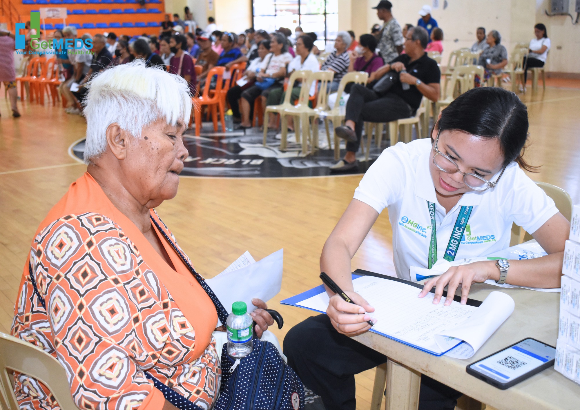 A Getmeds Healthcare team member assisting an elderly patient at a community medical outreach event, representing Getmeds Healthcare's role in connecting patients with essential medicines.
