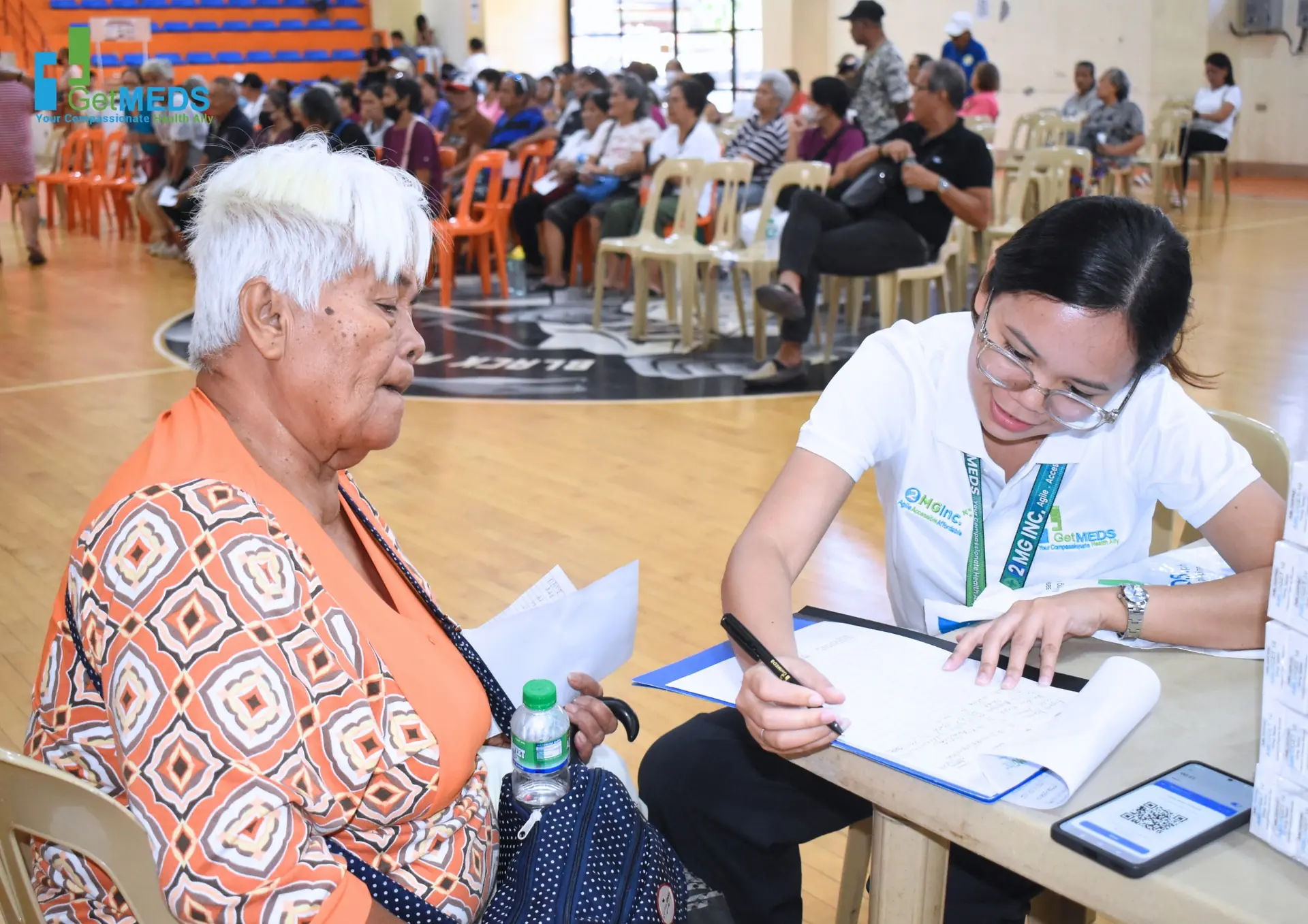 A Getmeds Healthcare team member assisting an elderly patient at a community medical outreach event, representing Getmeds Healthcare's role in connecting patients with essential medicines.